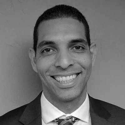 Black and white photo of a smiling man in a suit and tie.