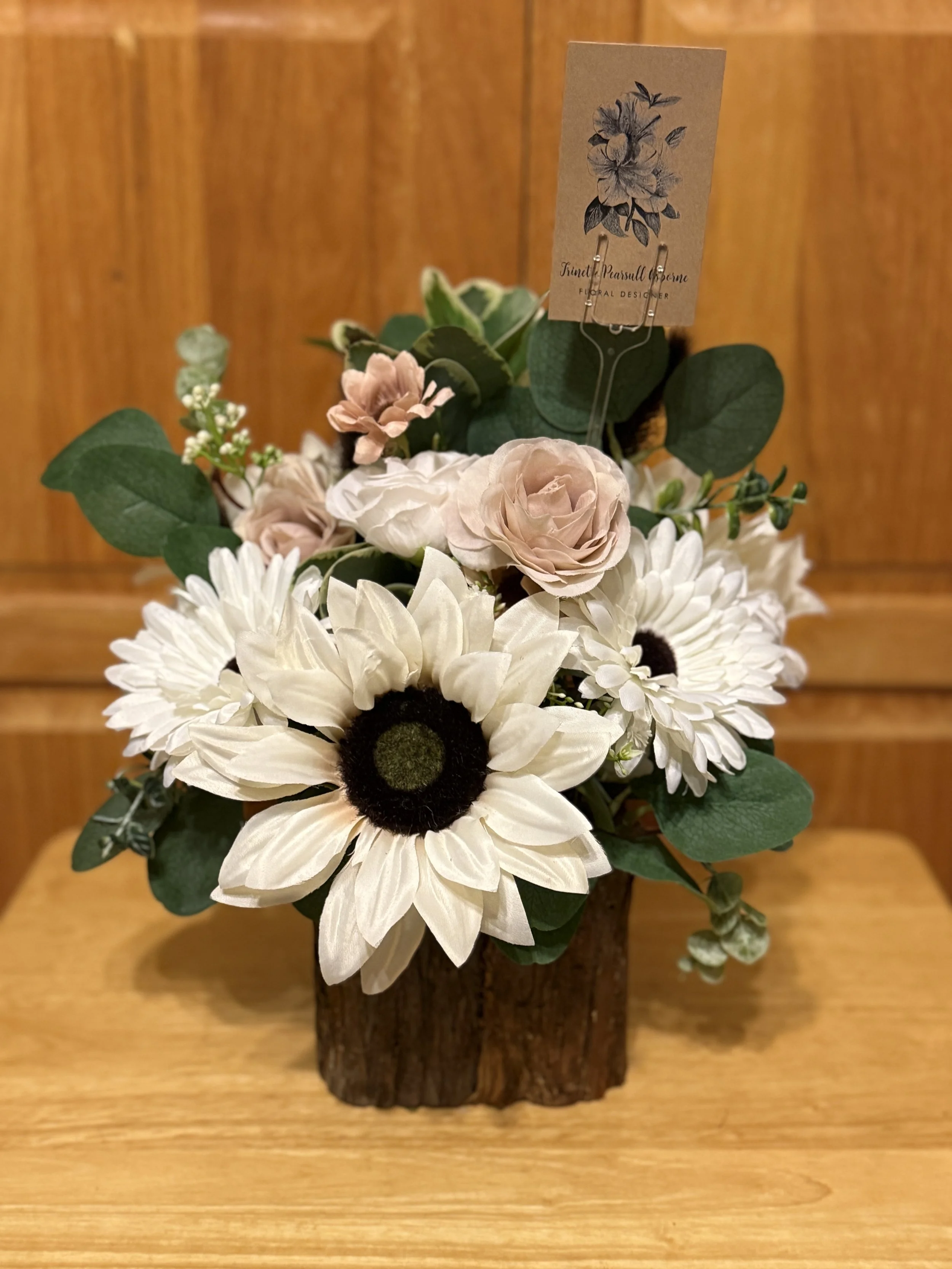 Artificial flower arrangement with white daisies, light pink roses, and greenery in a wooden container.