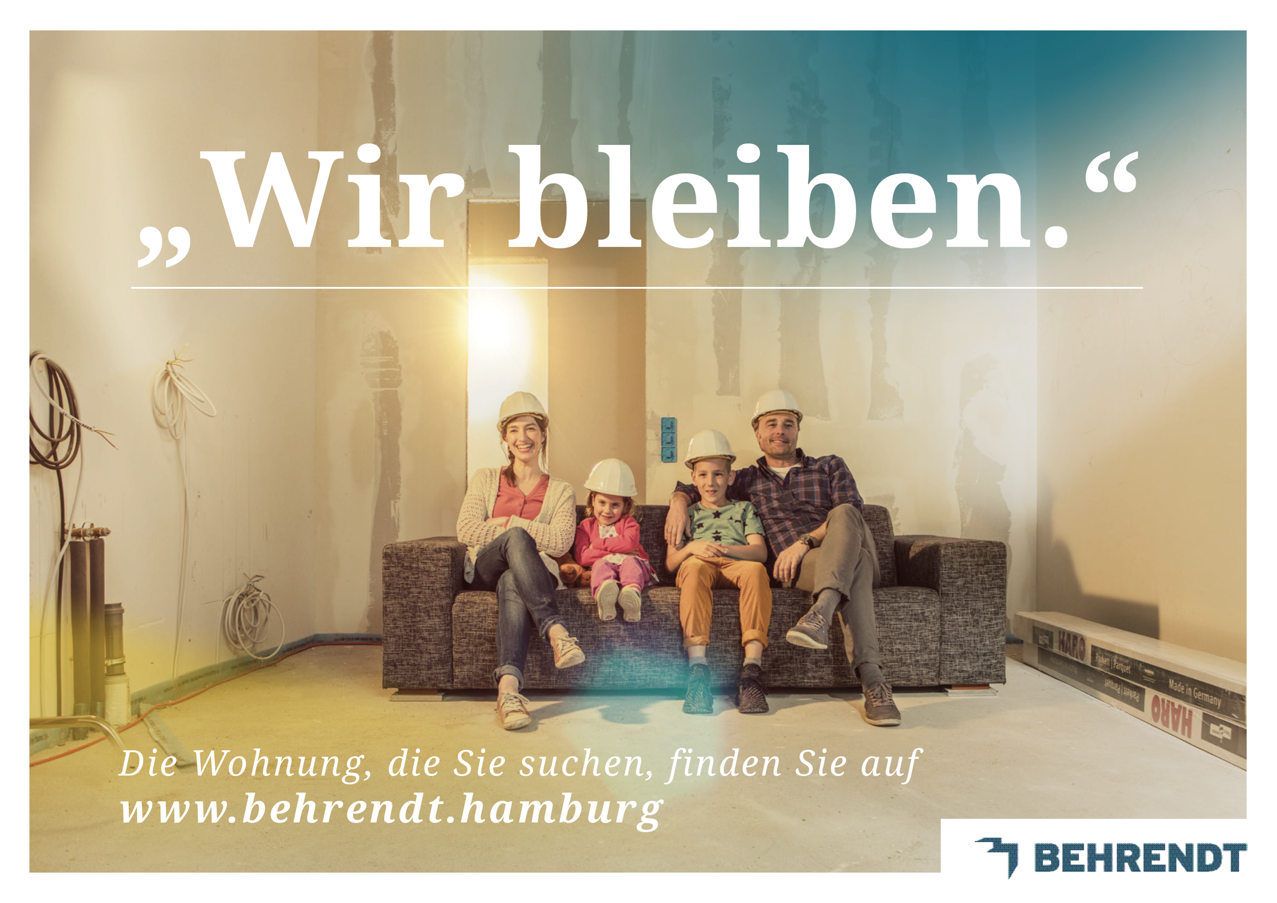 Familie mit drei Kindern und zwei Erwachsenen in einer unfertigen Wohnung, alle tragen Helme, sitzen auf einem Sofa und lachen. Der Raum ist im Bau, die Wände sind unverbaut. Es gibt Baumaterial auf dem Boden und Kabel an der Wand.