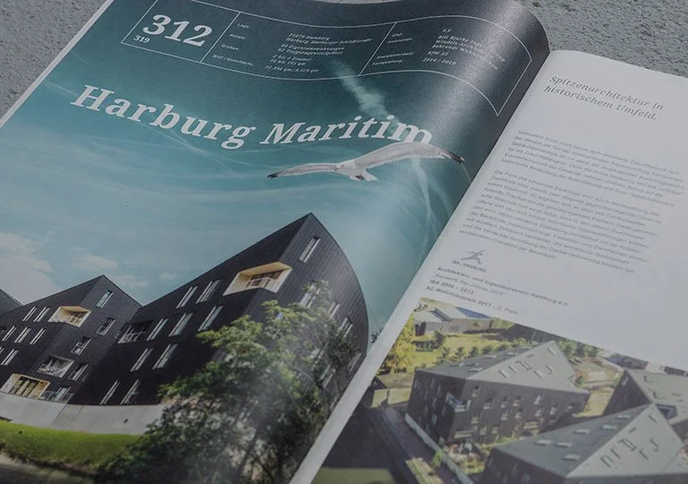 Offen illustriertes Magazin mit Artikeln und Bildern über maritime Architektur in Harburg, Hamburg, inklusive moderner Gebäude mit dunklem Fassadendesign und einem Flugzeug über dem Wasser.