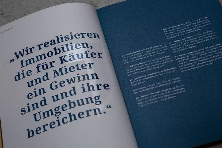 Offene Broschüre mit einem Zitat auf der linken Seite in dunkler Schrift auf weißem Hintergrund, rechte Seite mit Textabschnitten auf blauem Hintergrund.