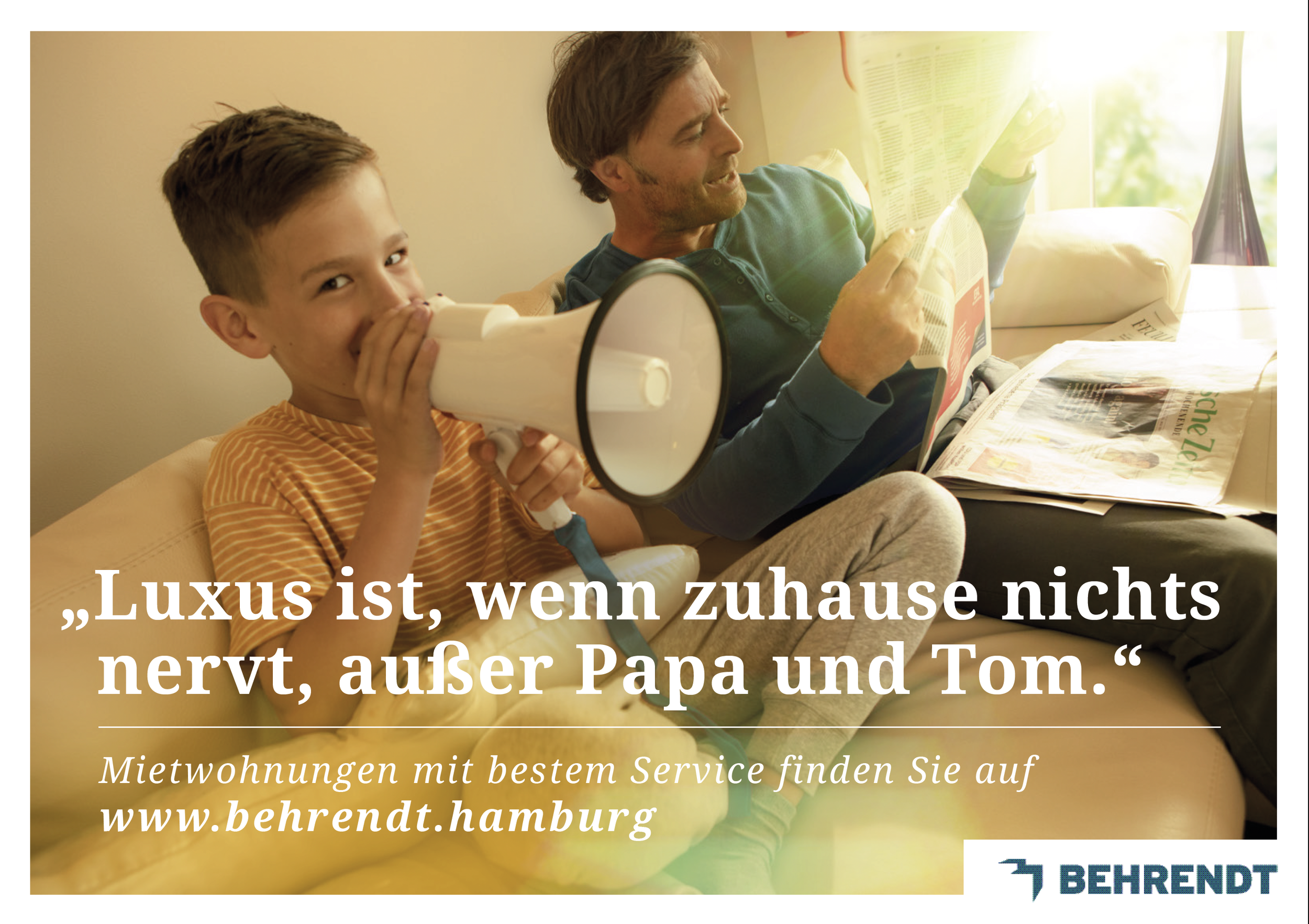 Ein Junge mit einem Megafon und ein erwachsener Mann lesen zusammen auf einem Sofa, umgeben von Zeitungen, in einem hell erleuchteten Raum.