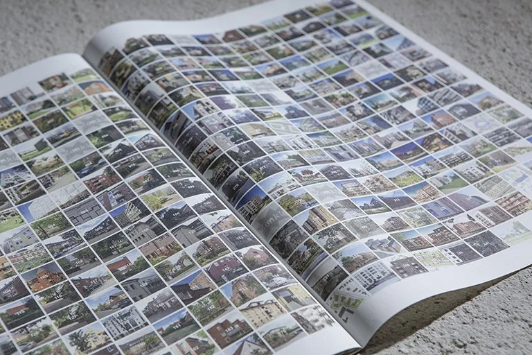 Ein offengelegtes Fotoalbum mit vielen kleinen, bunten Bildern auf Papier, das auf einem Tisch liegt.