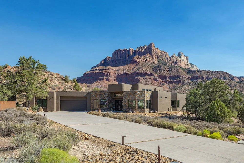 Modern house with stone and stucco exterior in a desert landscape with a mountain in the background