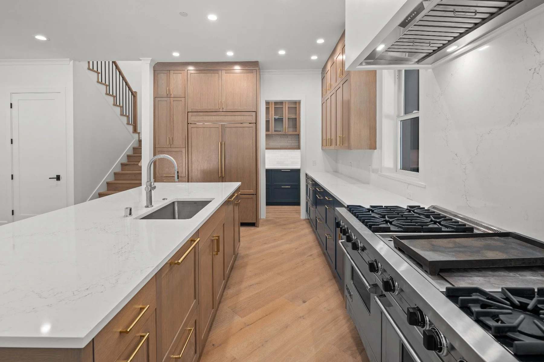 Modern kitchen with wooden cabinets, a white marble island, and a stainless steel stove and oven.