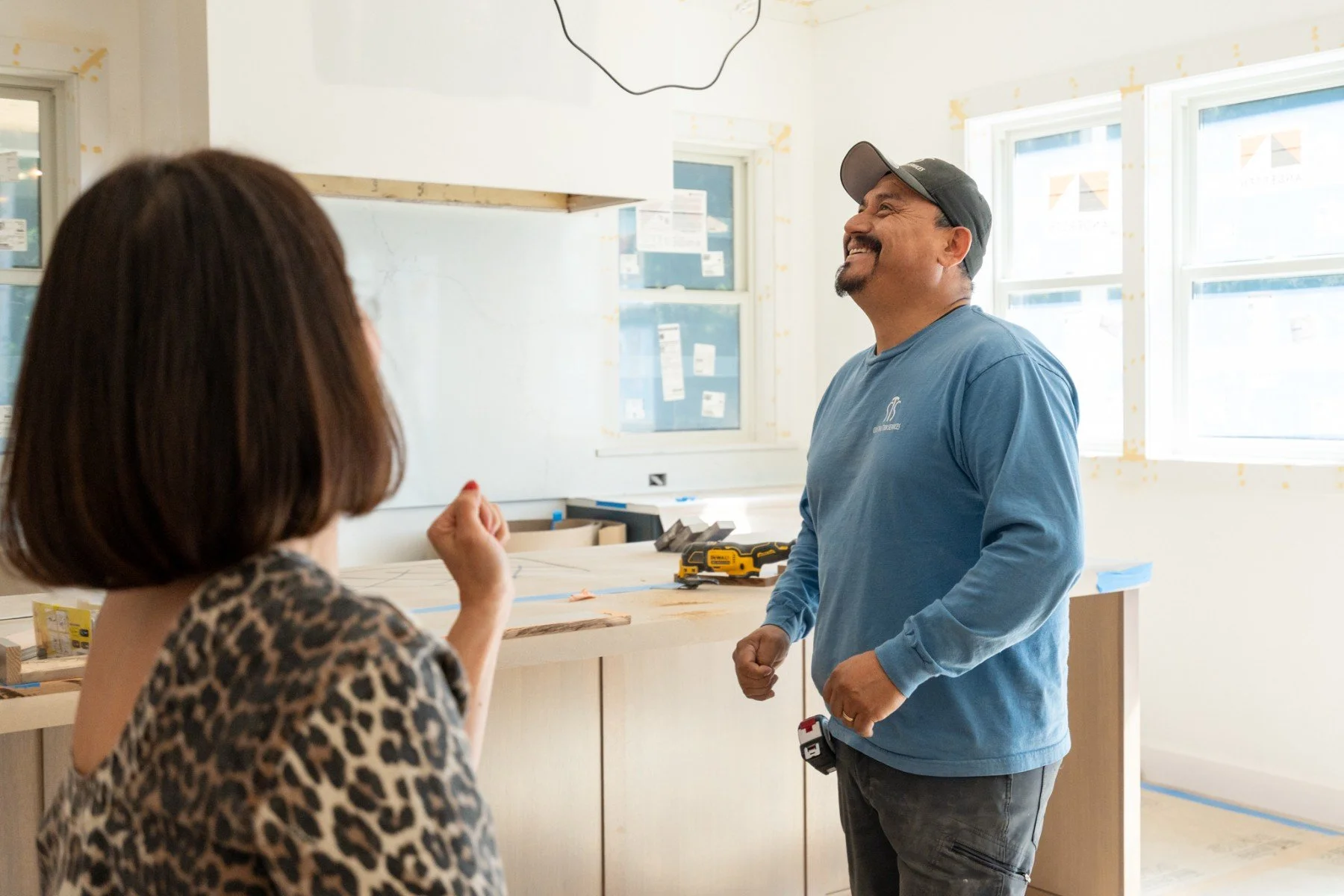 A man and woman talking in a room under construction, with work tools on a counter and unfinished walls