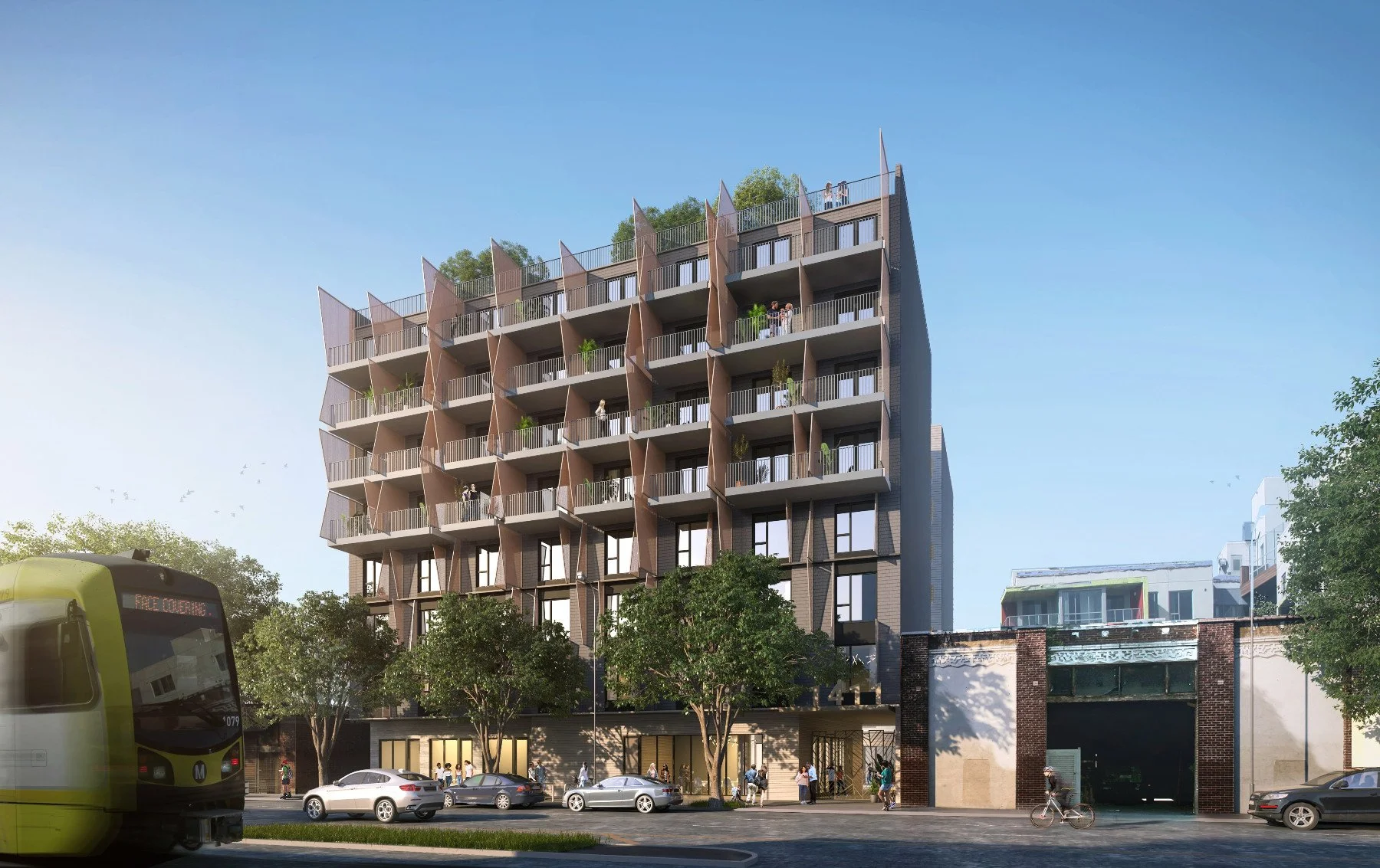 A modern multi-story residential building with balconies, trees in front, cars parked, and a bus on the street during daytime.