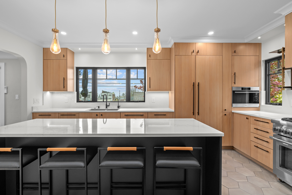 Modern kitchen with wooden cabinets, a white marble island, and a stainless steel stove and oven.