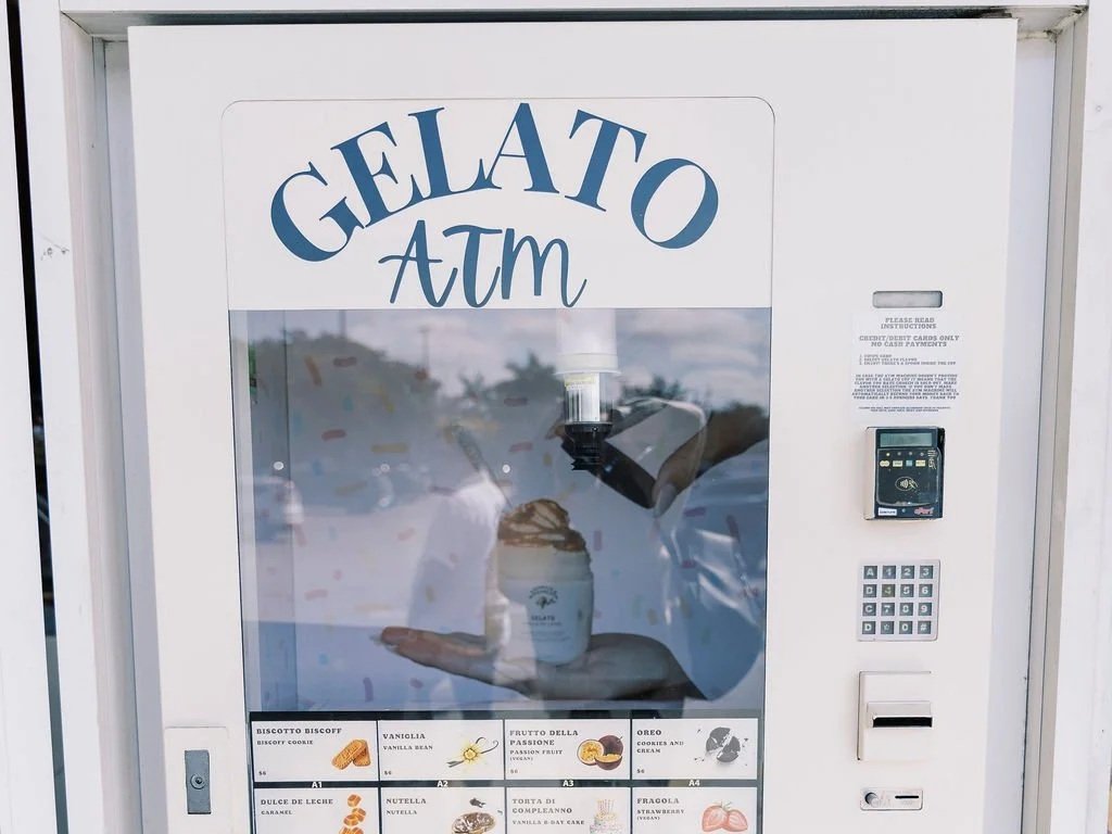 Vending machine with a sign reading 'Gelato ATM' at the top, displaying different gelato flavors, including Biscotto Biscow, Vanilla Bean, Frutto Della Passione, Oreo, Dulce De Leche, Nutella, Torta Di Cioccolato, and Pirogola.