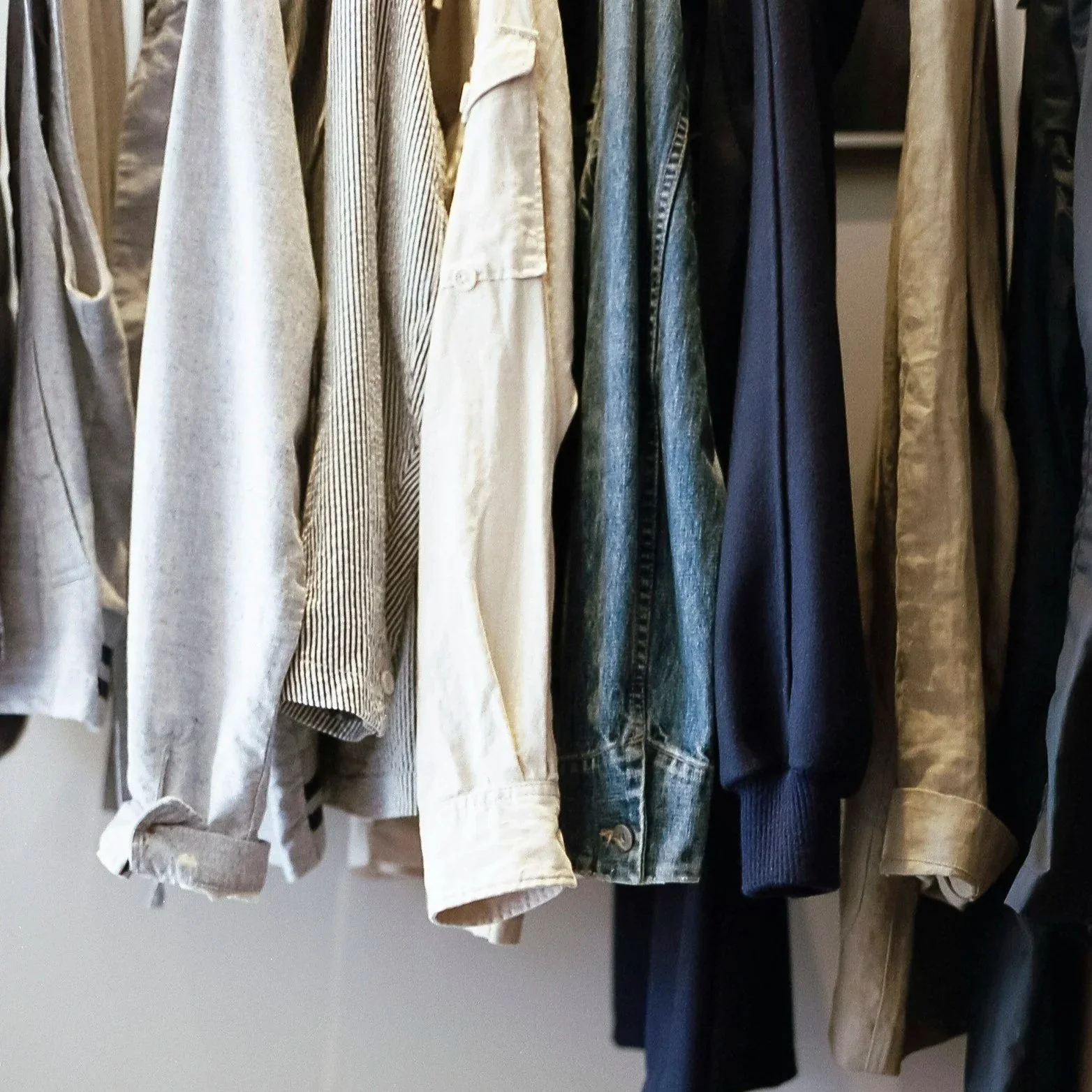 A row of hanging casual and denim jackets in various shades and patterns.
