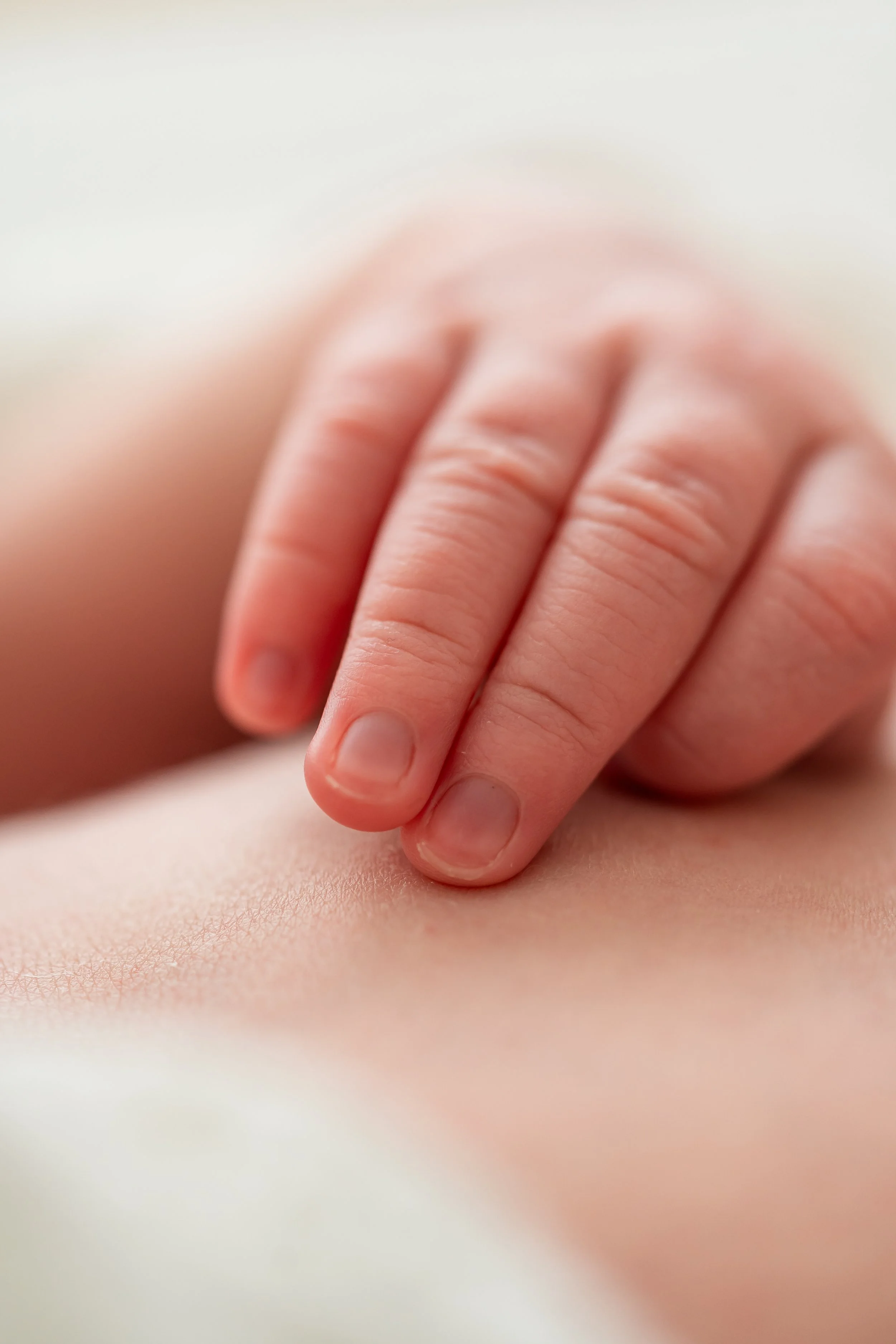 Close-up macro of a newborn’s tiny hand resting on a soft surface during a lifestyle newborn photoshoot in Geneva