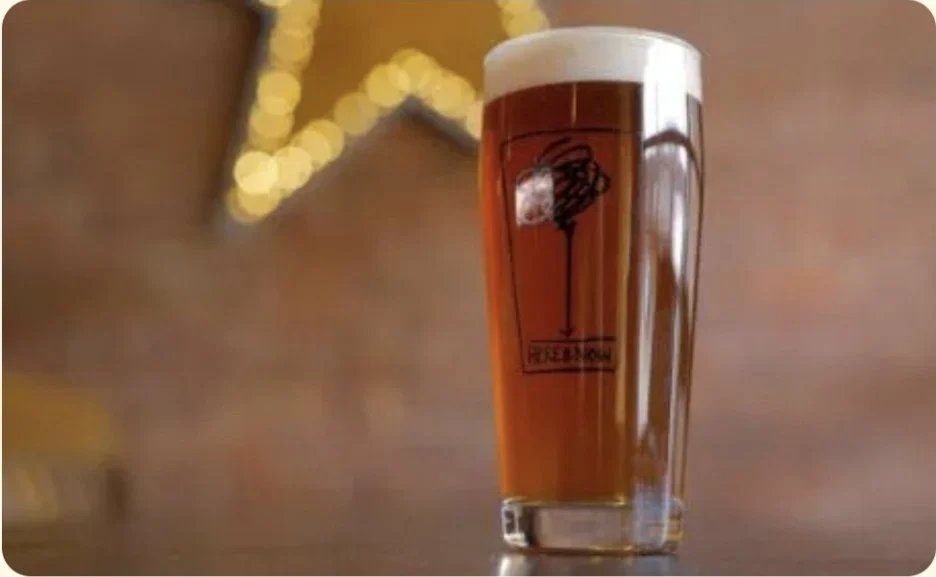 An Irish red ale in front of a decorative start light in our exposed brick dining room at here and now brewing company in honesdale pa