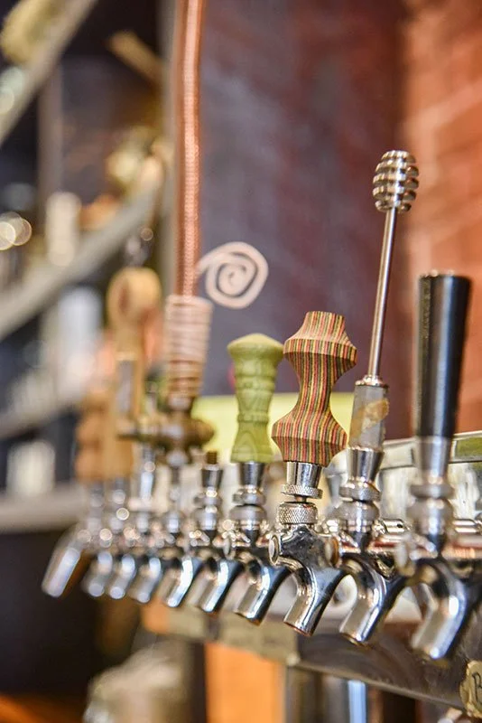 Close-up of beer taps with unique, hand made, colorful, patterned handles in a bar setting at here and now in honesdale.