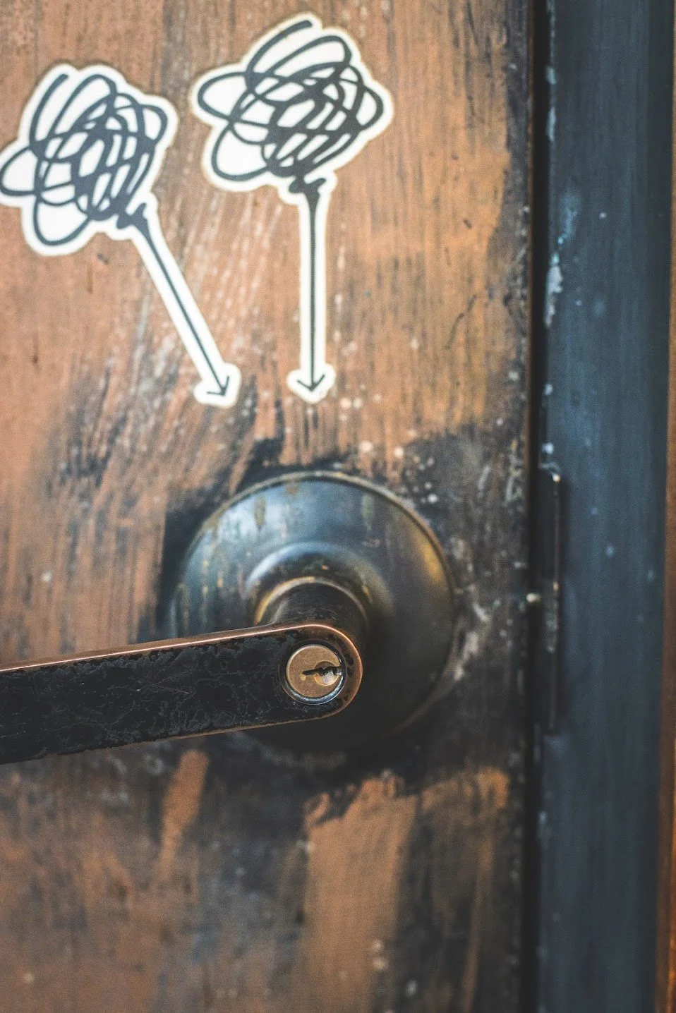 A close-up of a wooden door with two logos above the doorknob, indicating where our entrance is located