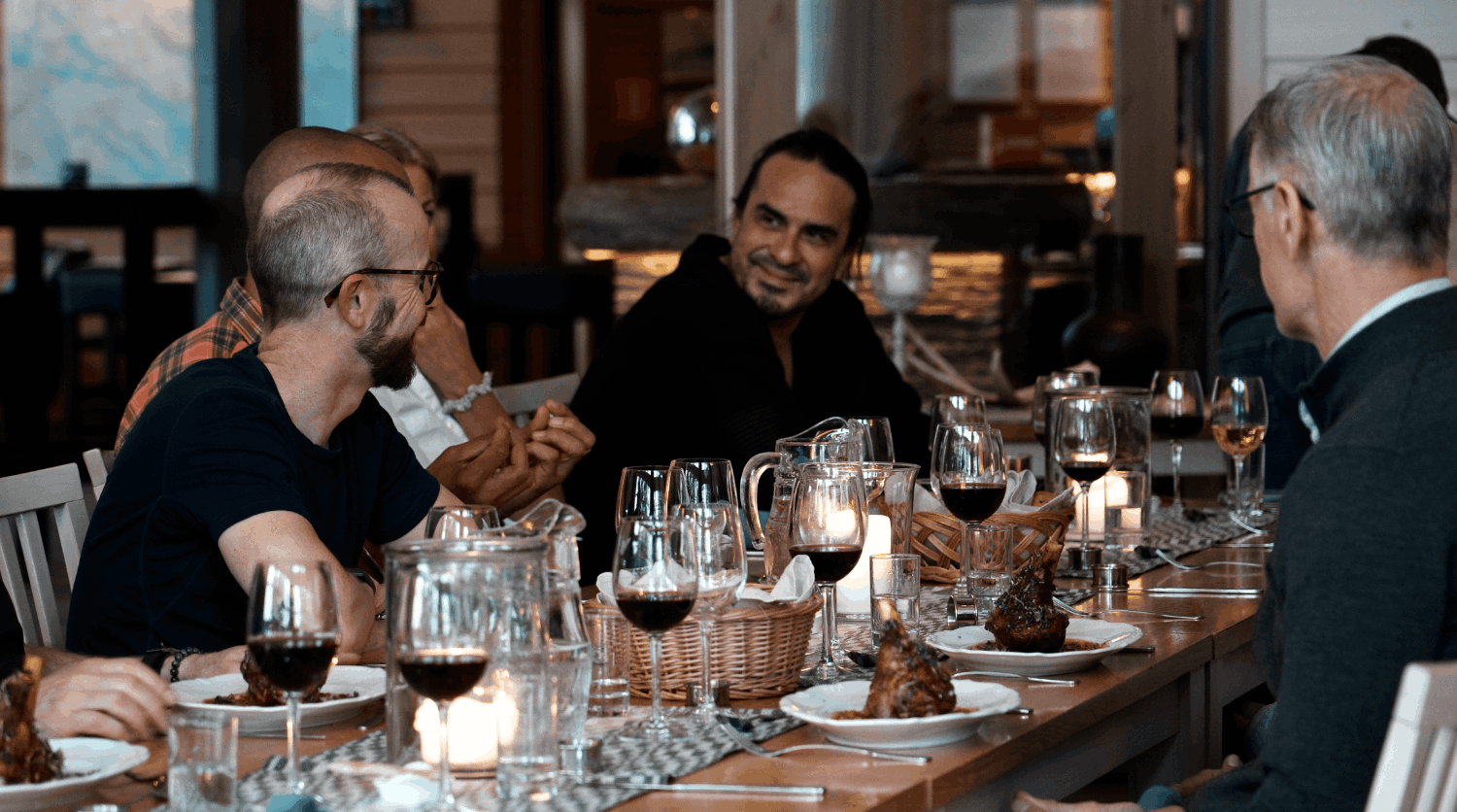 Måltid med flera personer som äter vid ett bord med glas vin och ljuslyktor.