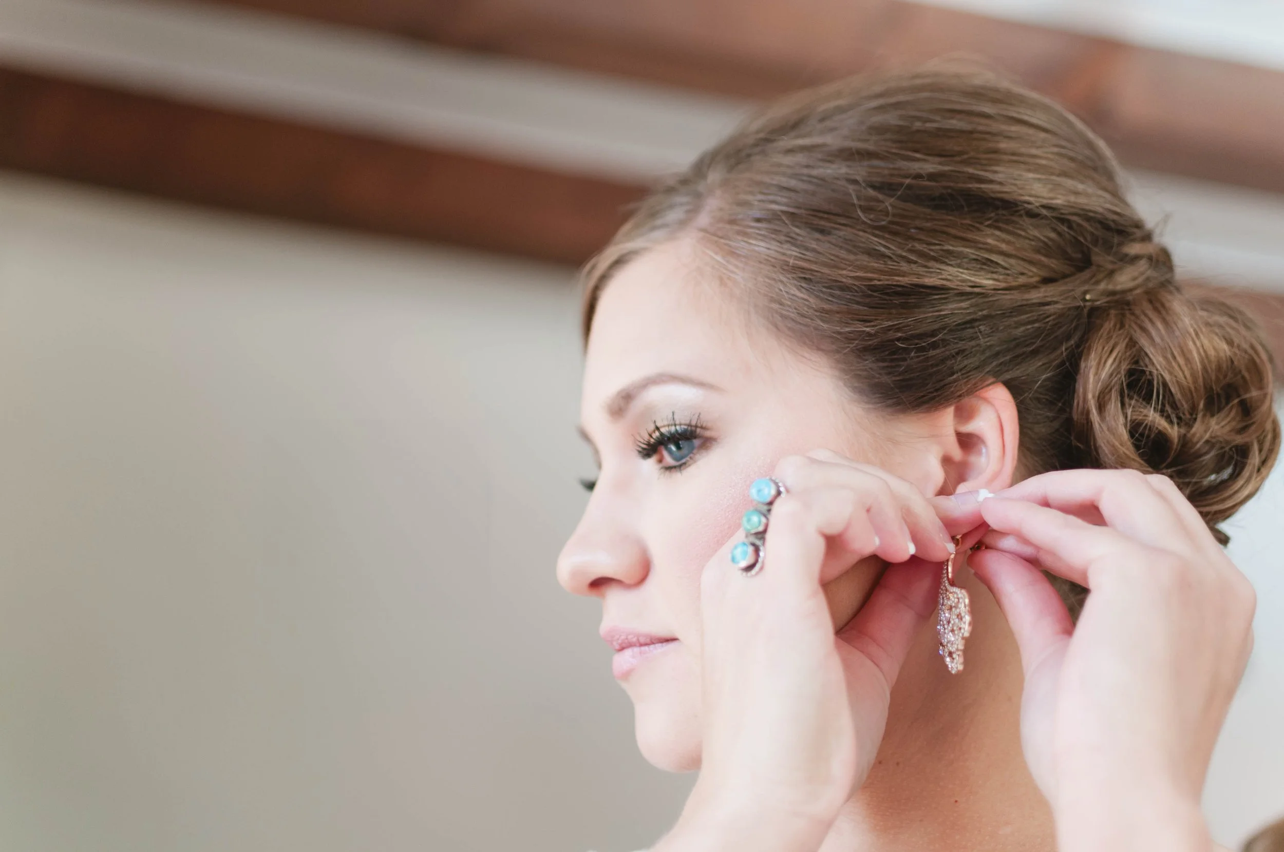 Woman with styled hair and jewelry putting on an earring.