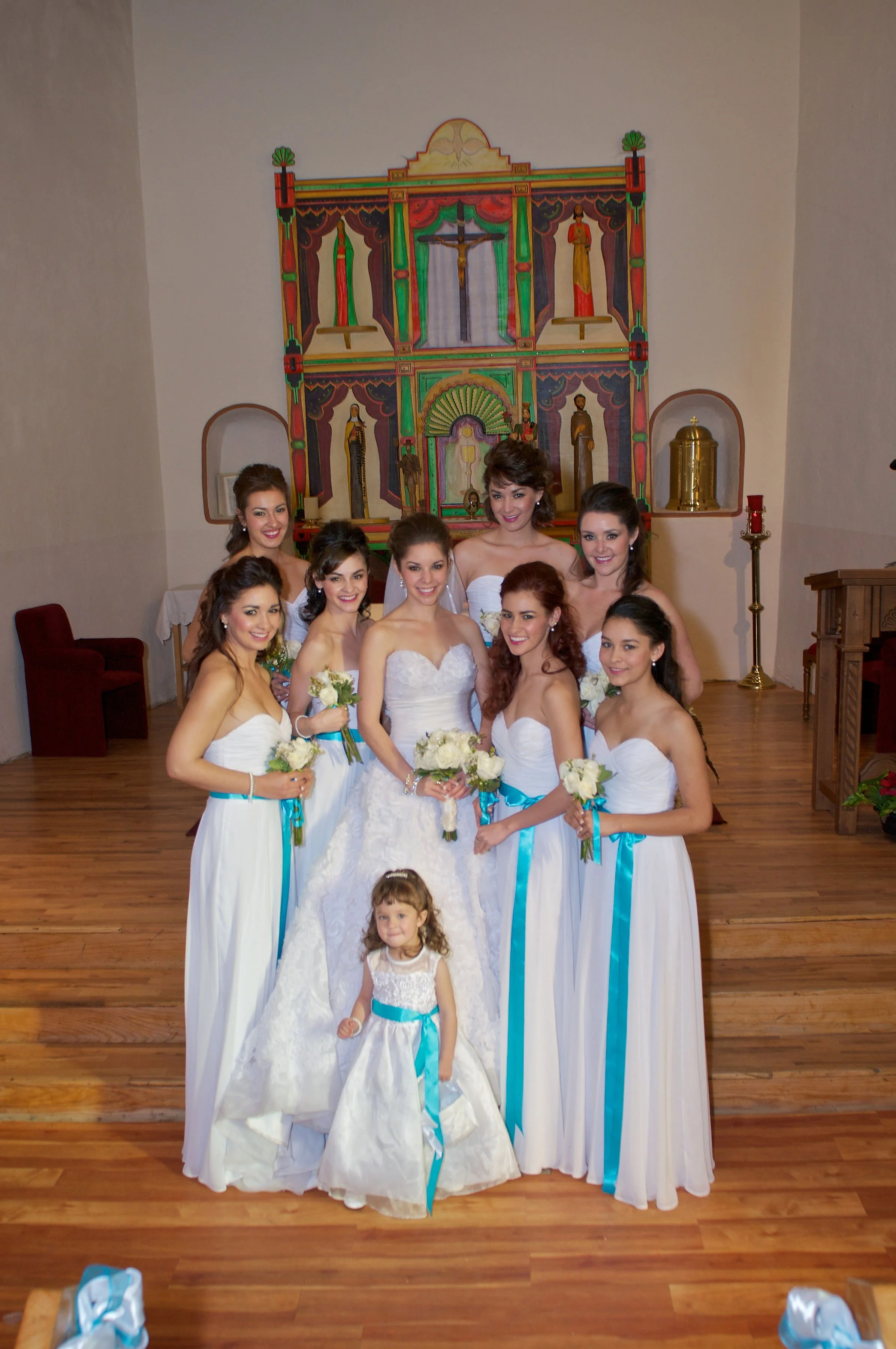 Group of women and girls, including a bride, posing in a church for a wedding photo