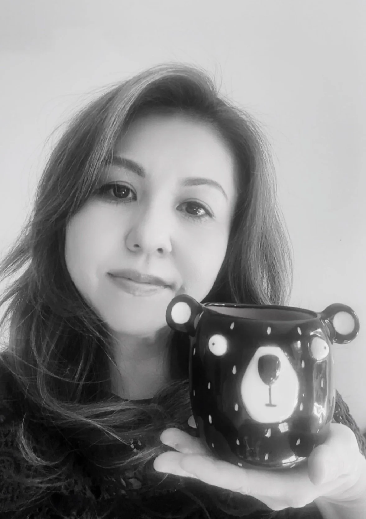 A woman with long hair holding a bear-shaped mug.