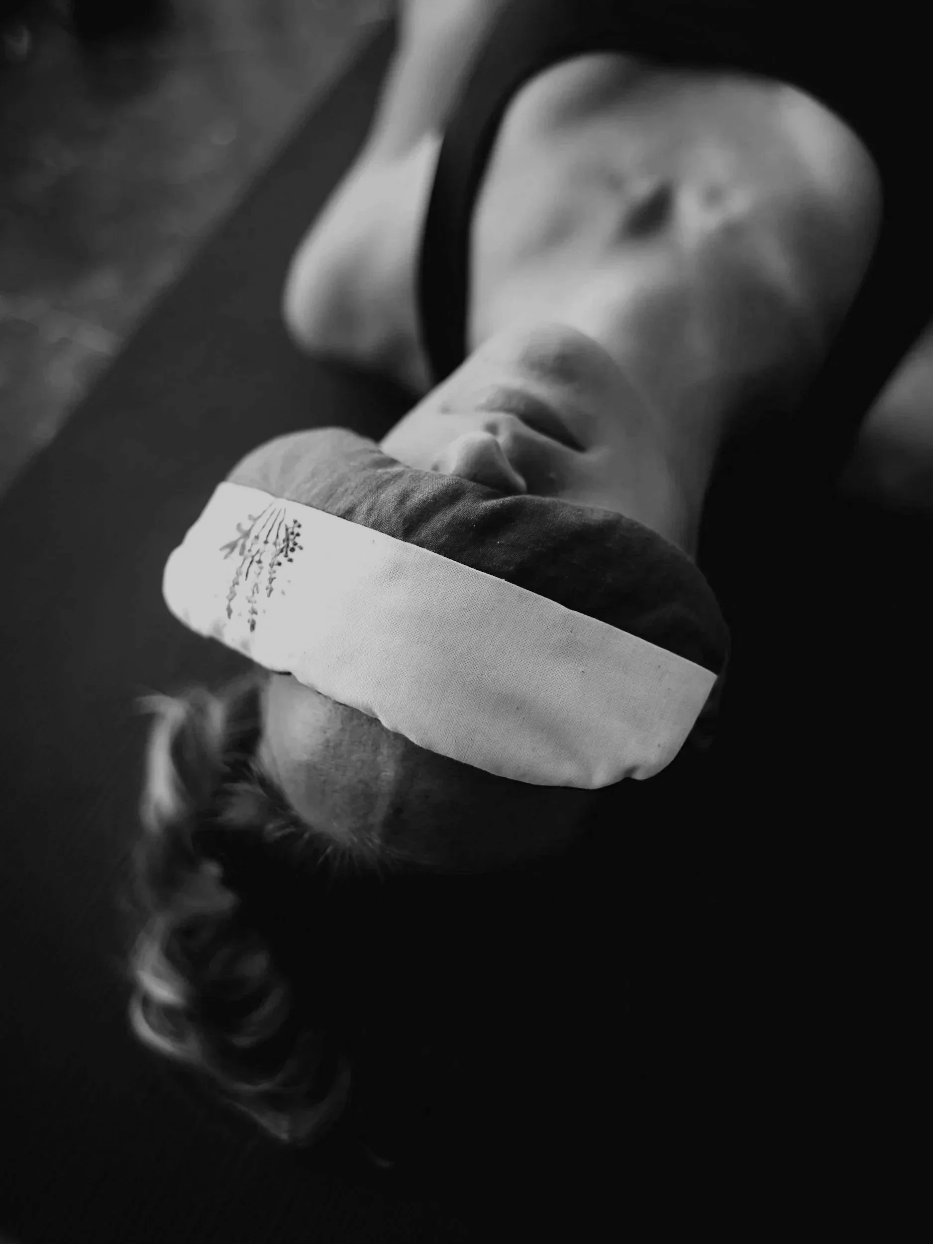 Woman resting in savasana with an eye mask during a restorative yoga class