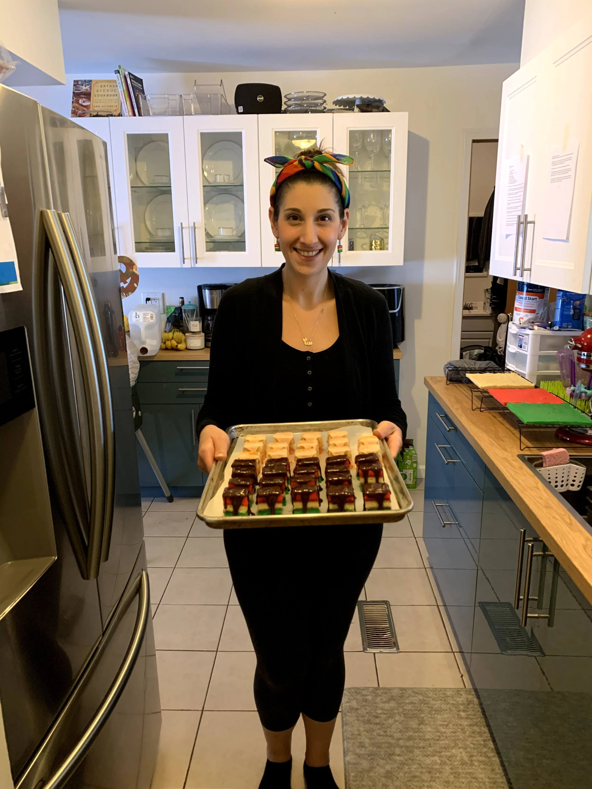 Smiling woman in a kitchen holding a tray of baked goods