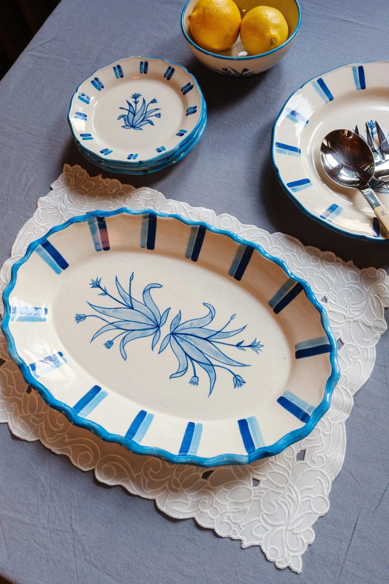 STUDIO PURANI Tulip serving platter in blue with matching Tulip dessert plates, dinner plates, and breakfast bowl holding lemons