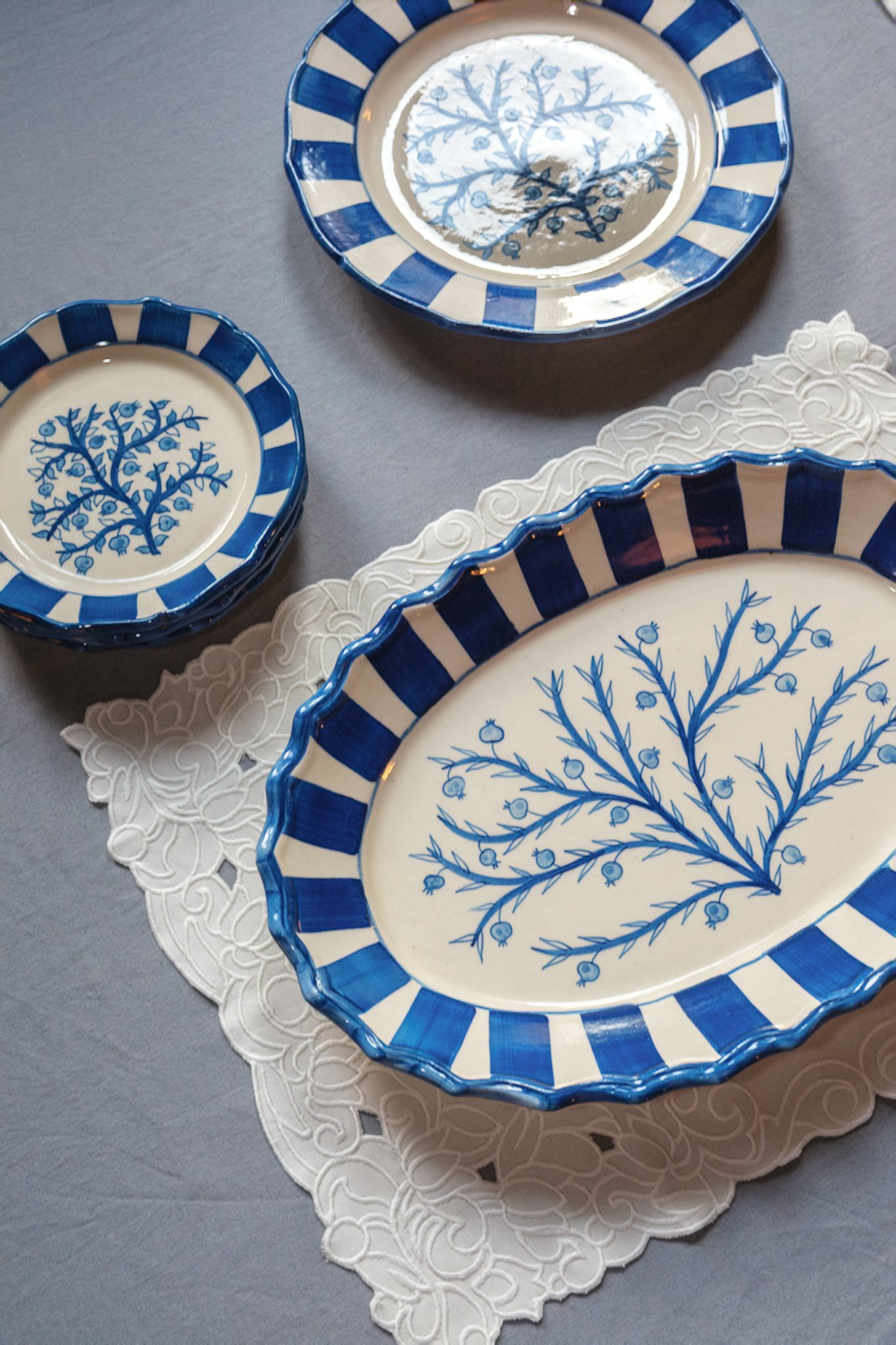 STUDIO PURANI Pomegranate serving platter in blue styled with matching stacked Pomegranate dessert plates and a Pomegranate dinner plate