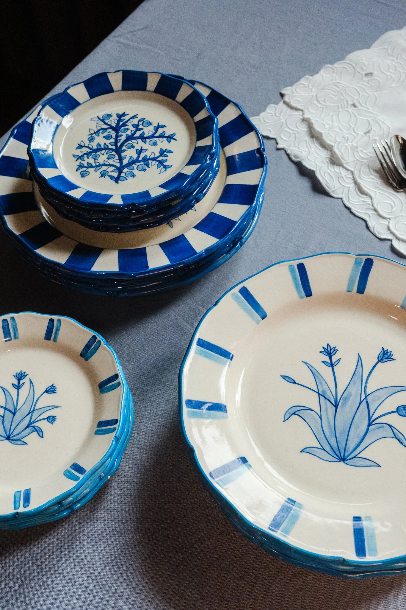 STUDIO PURANI Tulip dinner plate in blue styled with matching Tulip dessert plates and stacked Pomegranate plates — hand-painted blue and white ceramic tableware