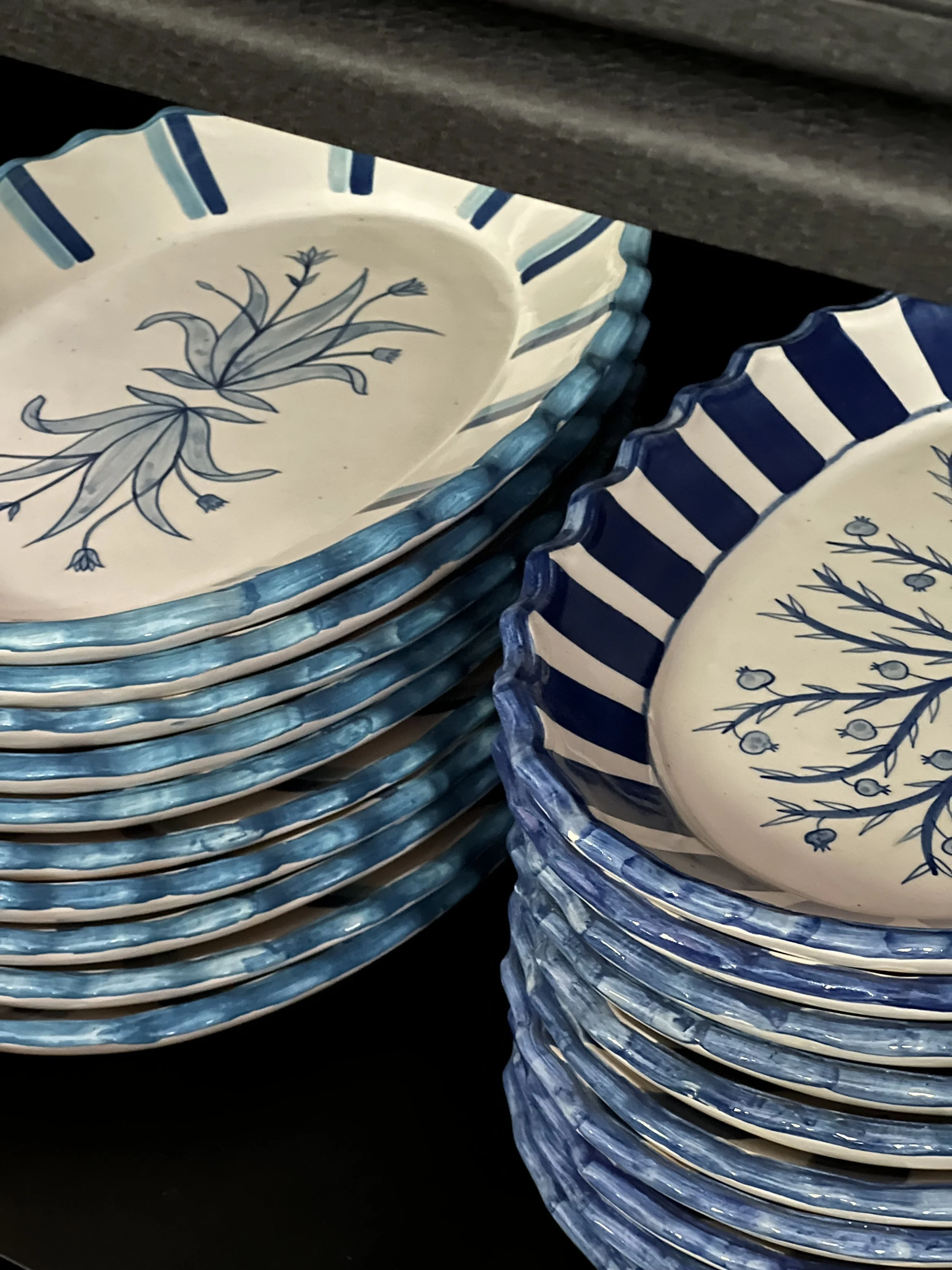 Stack of STUDIO PURANI Tulip and Pomegranate oval serving platters in blue, shelved in the studio office