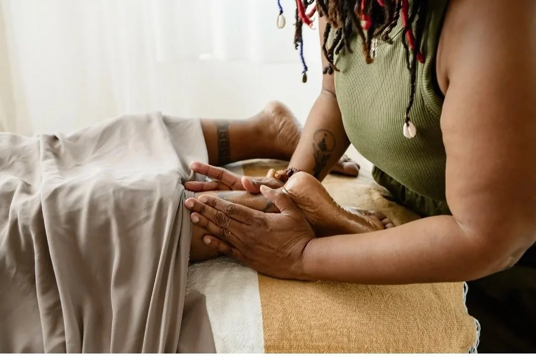 A person giving a foot massage to another person lying down  massage table.