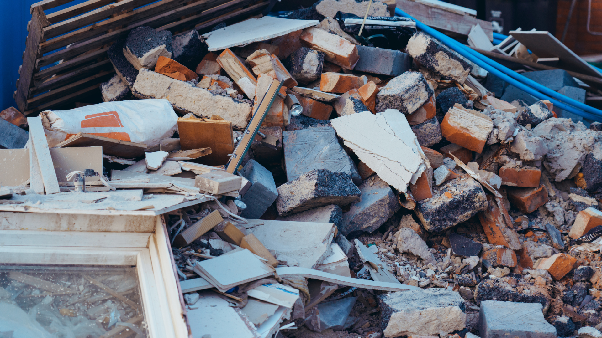 Pile of construction debris including bricks, broken tiles, plaster, and scattered building materials.
