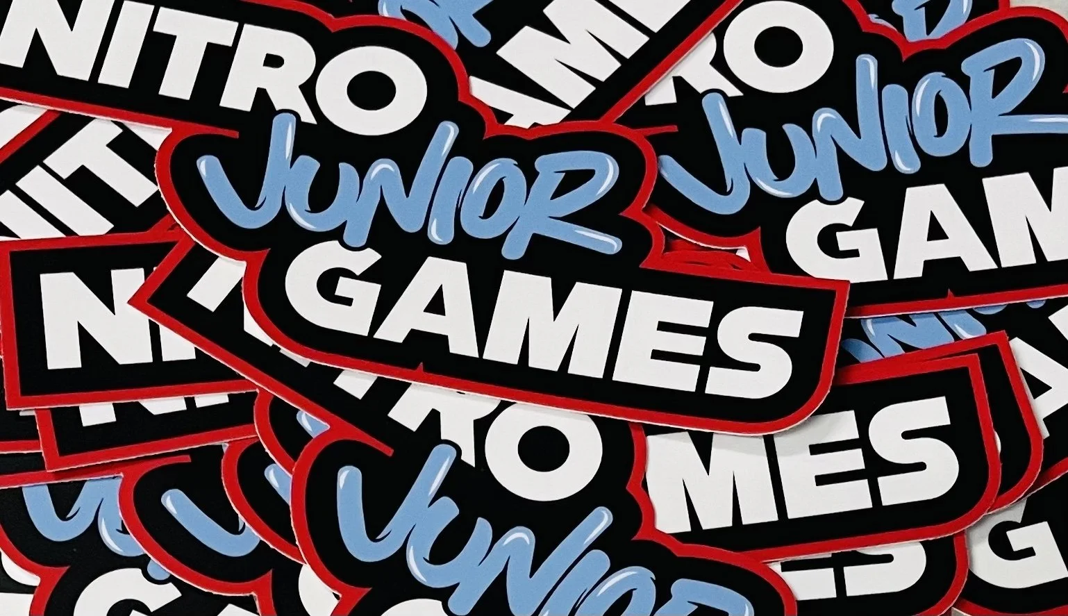 A collection of stickers with words "NITRO," "JUNIOR," and "GAMES" in various colors and styles, with overlapping design and black, white, blue, and red color scheme.