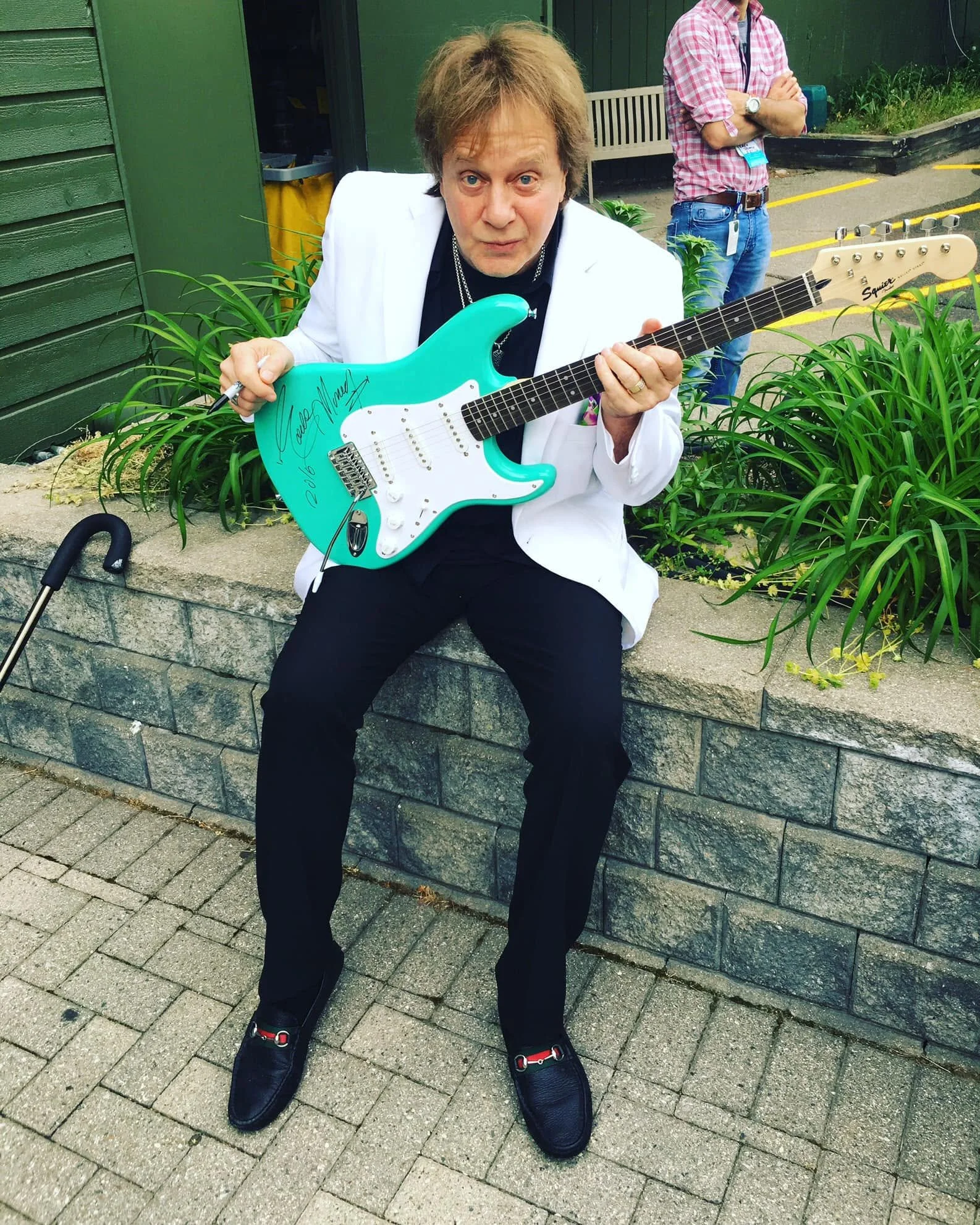 Eddie Money holding the guitar he signed.