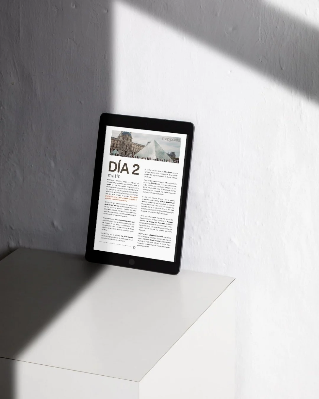 Una tableta digital en una mesa blanca, mostrando un periódico en español con el titular 'DÍA 2'.