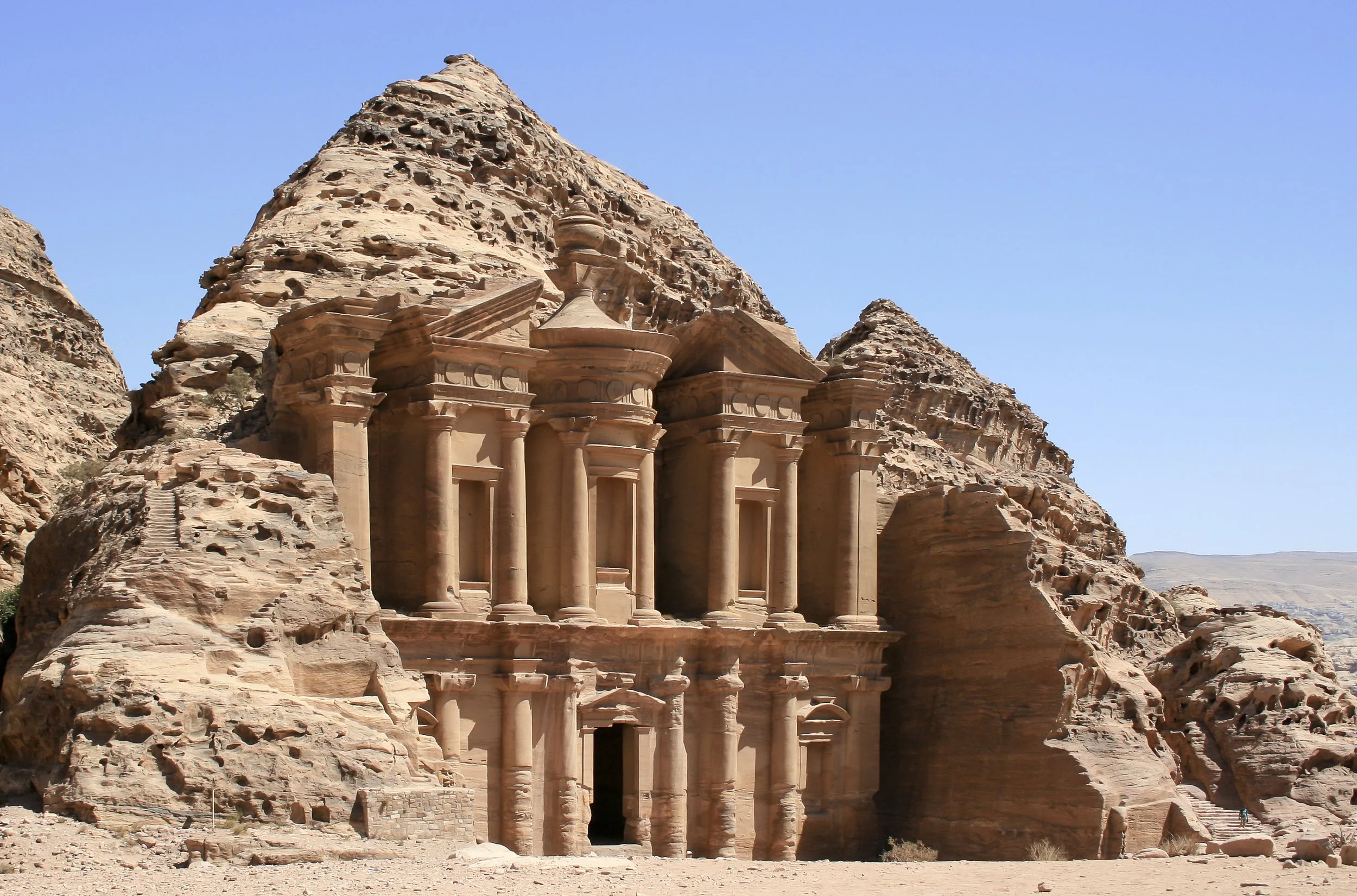 La antigua ciudad de Petra en Jordania, famosa por sus esculturas en roca roja, con la fachada del Tesoro tallada en la piedra y rodeada de formaciones rocosas.