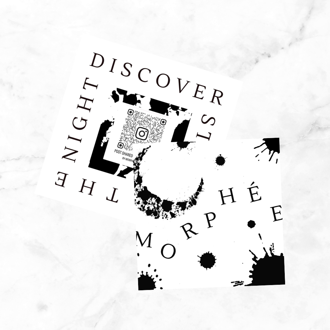 Two black and white abstract cards with text and paint splatters on a white marble surface. One card says 'Discover the Night' and the other 'Morphe'.