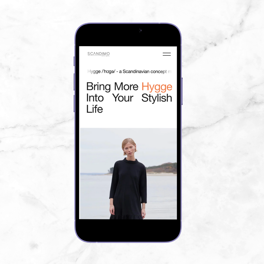 A smartphone displaying a webpage with the title 'Bring More Hygge Into Your Stylish Life' and an image of a woman in a black dress standing by the water.