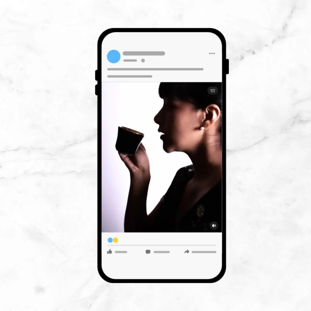 Silhouette of woman holding a small cup, viewed on a smartphone screen.