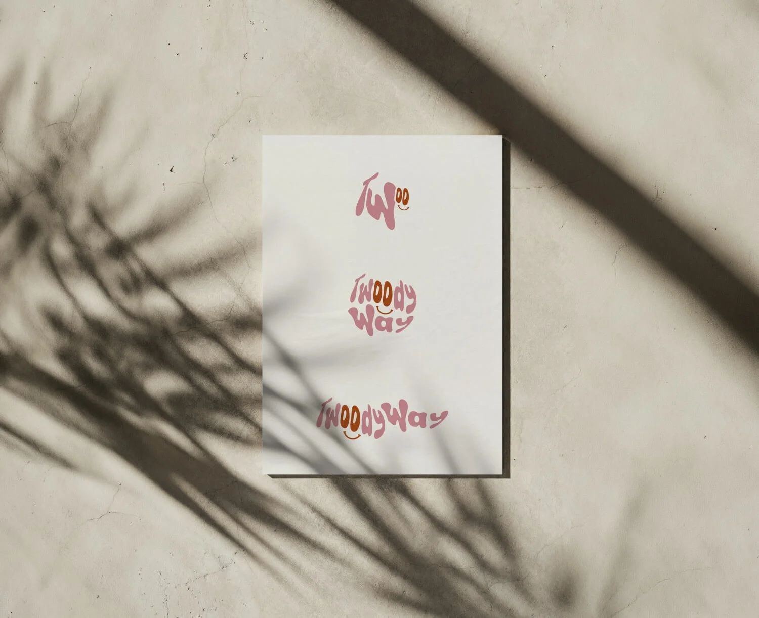 Une affiche blanche avec le logo "Twoody Way" écrit en lettres roses et brunes décliné en plusieurs formats, accompagnée d'un smiley, placé sur une affiche beige avec des ombres de branches dessiné dessus.
