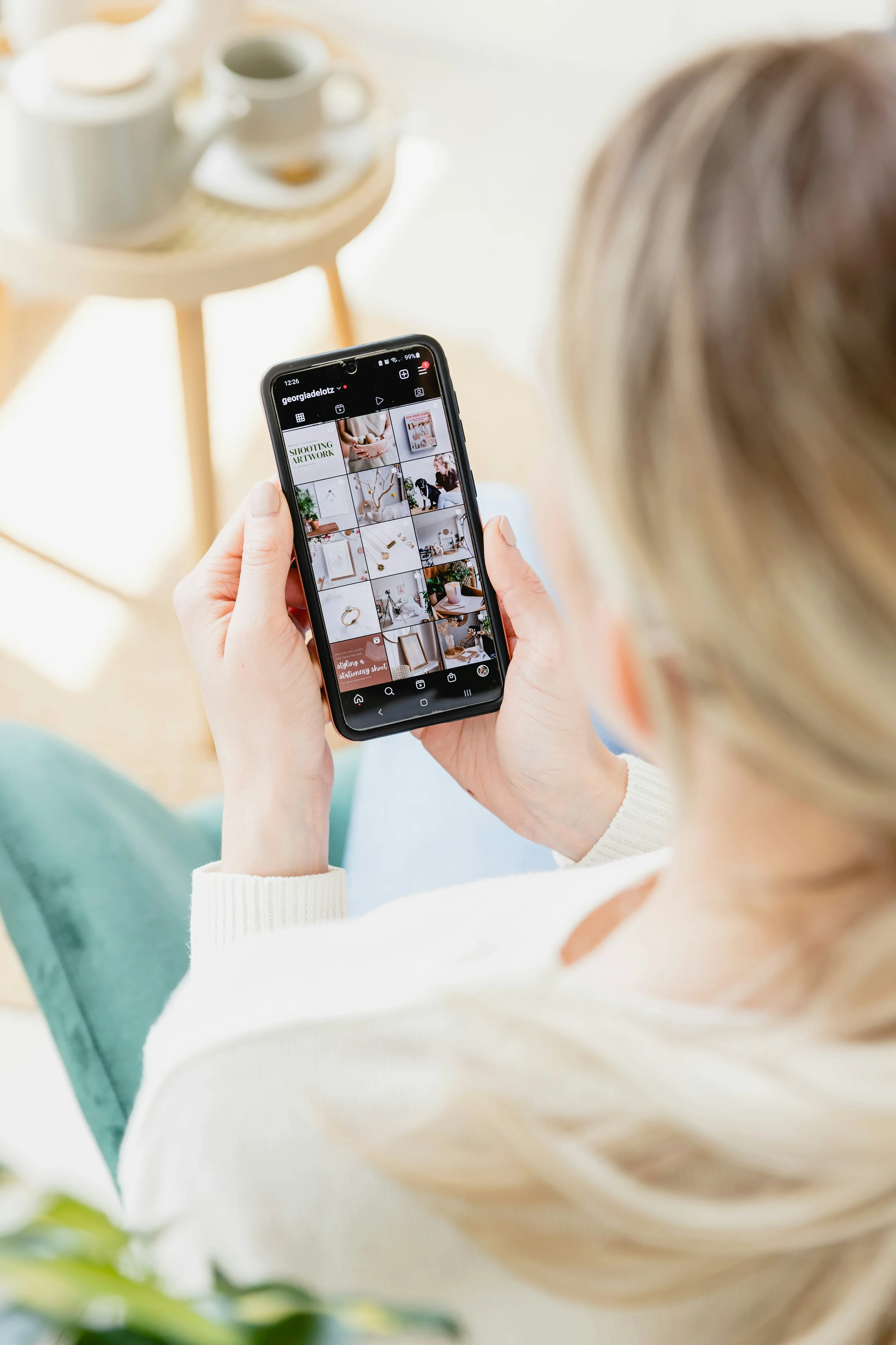 Une personne tient un téléphone portable montrant un profil Instagram avec plusieurs photos de décoration intérieure et d'accessoires.