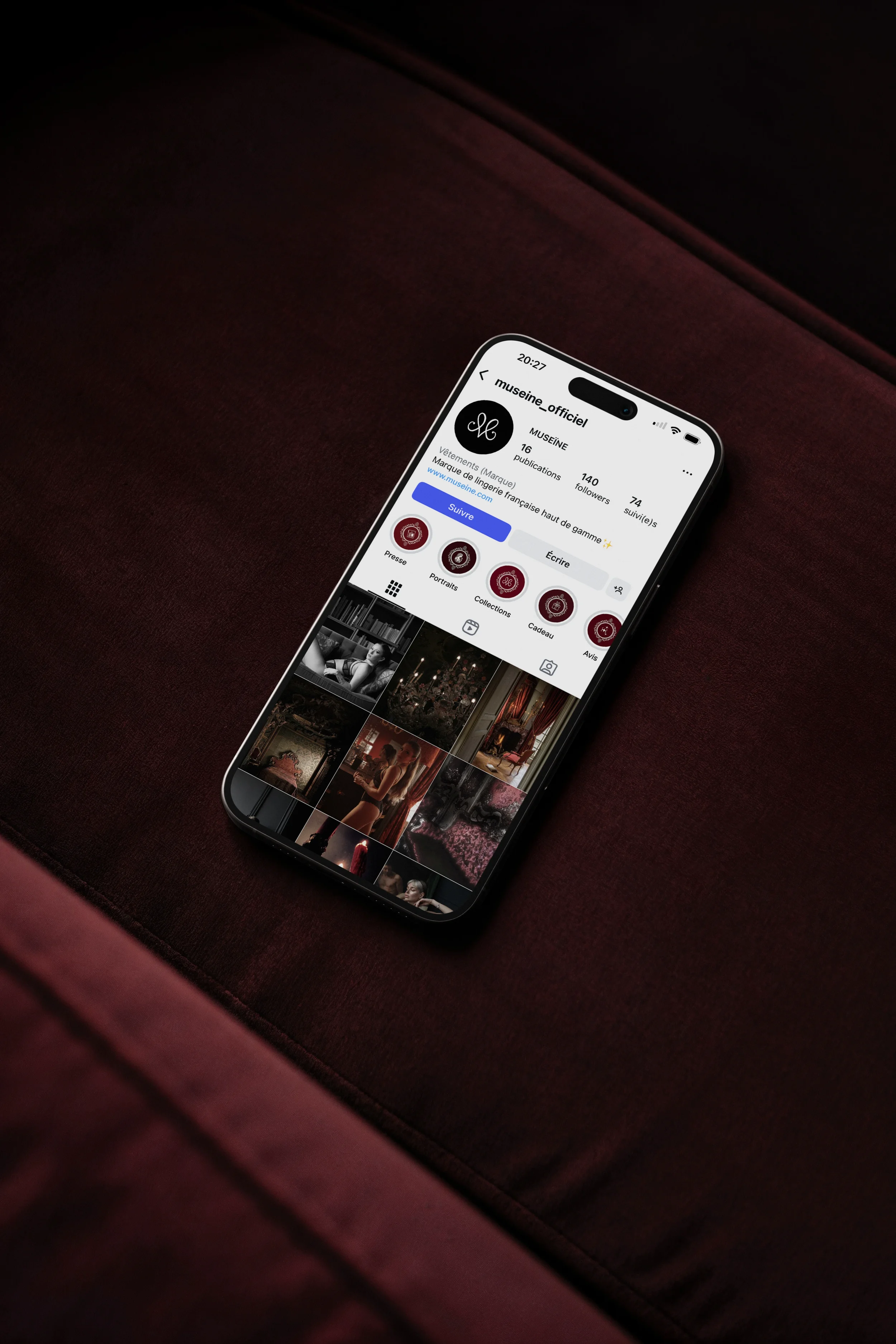 Téléphone portable affichant le profil Instagram de museine_officiel, un compte de marque de lingerie française, posé sur un fauteuil en velours rouge foncé.