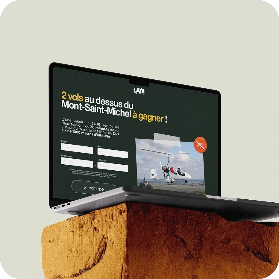 Un ordinateur portable affichant un concours pour gagner deux vols au-dessus du Mont-Saint-Michel, placé sur une pierre.