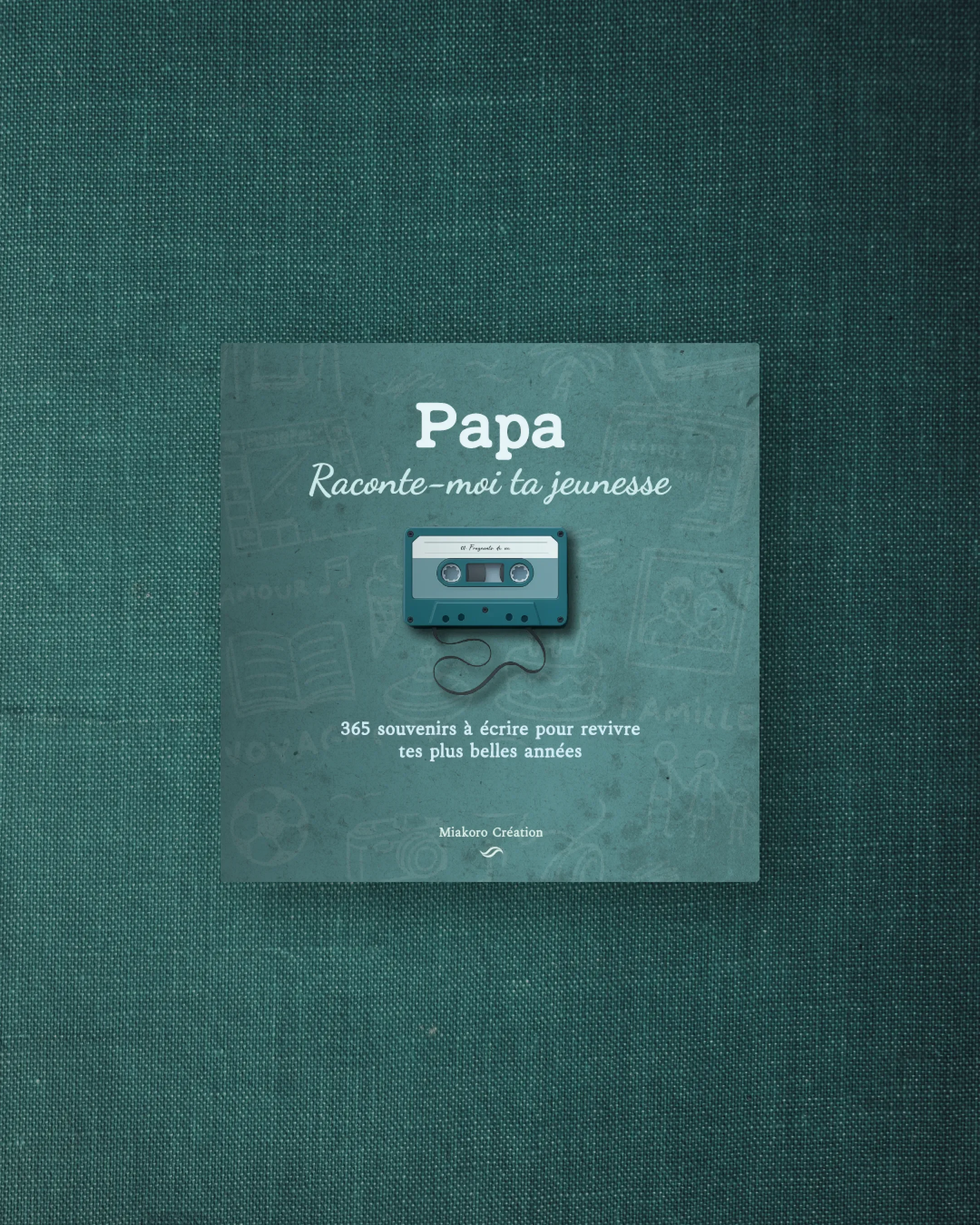 Un livre intitulé 'Papa Raconte-moi ta jeunesse' avec une illustration d'une cassette audio dessus, posé sur une surface vert foncé.