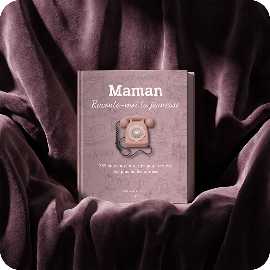 Couverture d'un livre intitulé 'Maman raconte-moi ta jeunesse', avec un ancien téléphone rose en façade, posé sur un tissu violet foncé