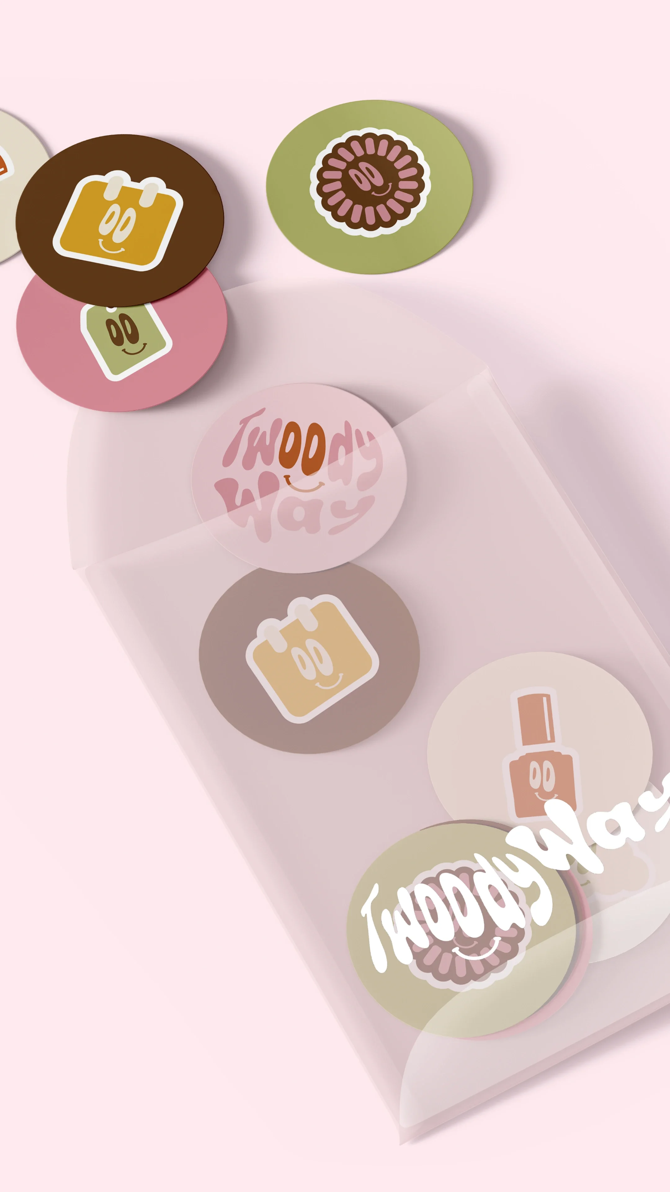 Petites figurines rondes avec des visages souriants, de différentes couleurs et motifs, dans une boîte en plastique sur un fond rose.