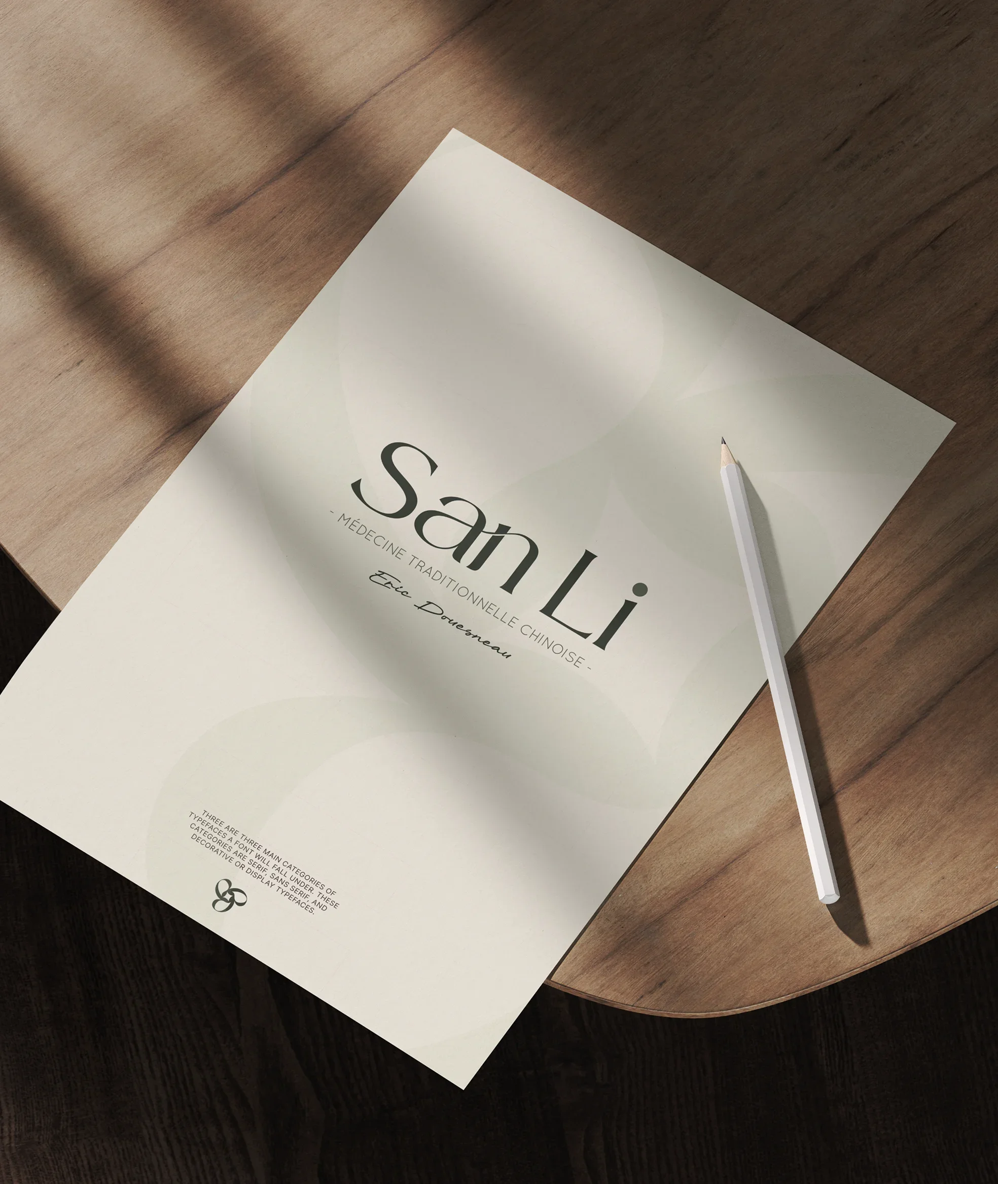 Une feuille de papier blanc avec le texte « San Li » et « Médecine Traditionnelle Chinoise » posée sur une surface en bois, accompagnée d'un stylo blanc.