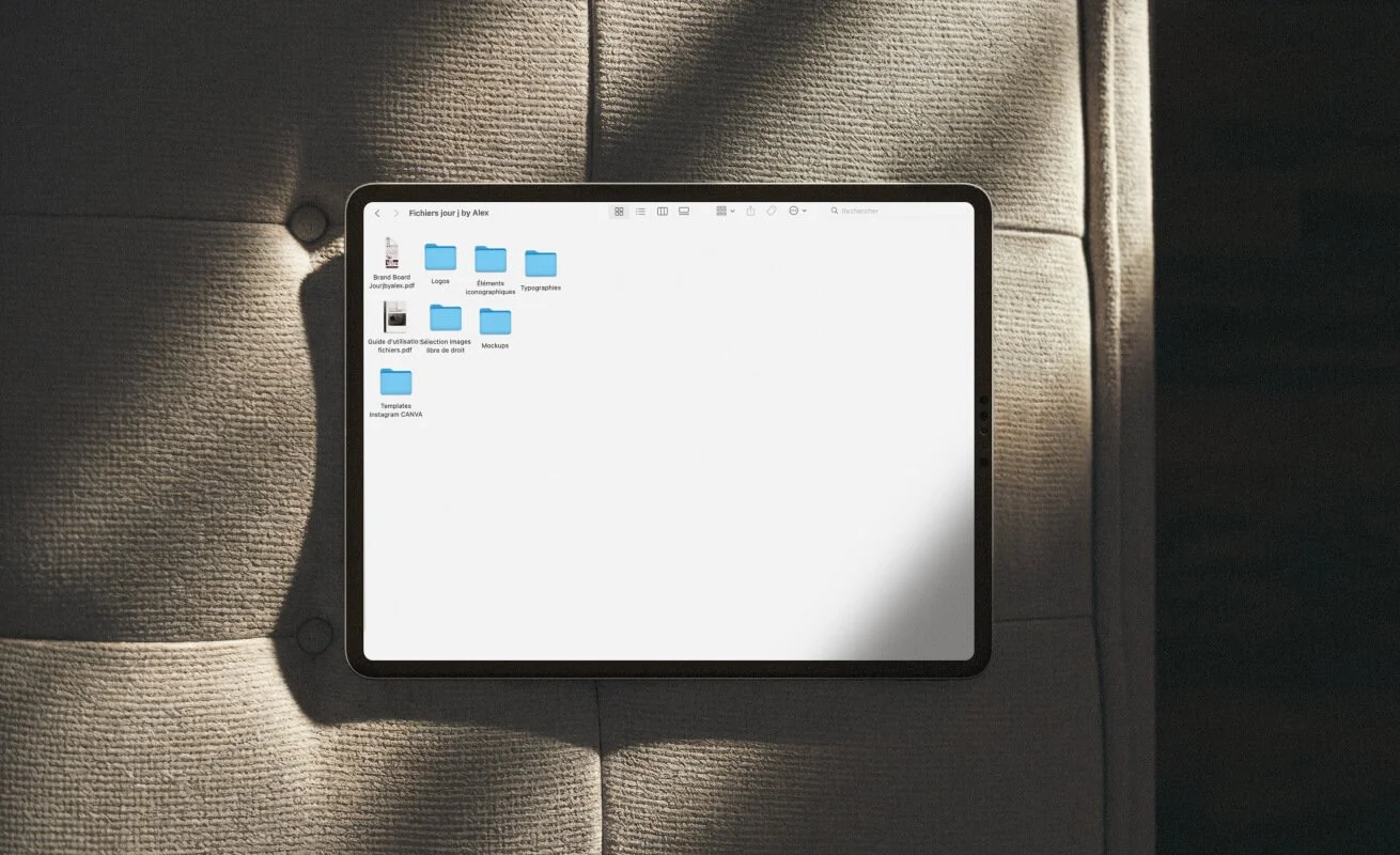 Tablette posée sur un canapé beige, affichant des dossiers et fichiers dans un gestionnaire de fichiers.