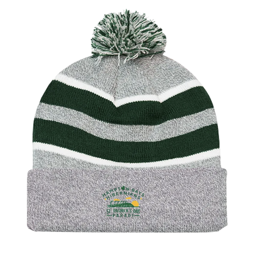 Gray knit winter hat with green, black, and white stripes and a pom-pom on top. Embroidered text on the folded brim reads 'Hampton Bays HibearnLans St. Patrick's Day Parade' along with a small American flag.