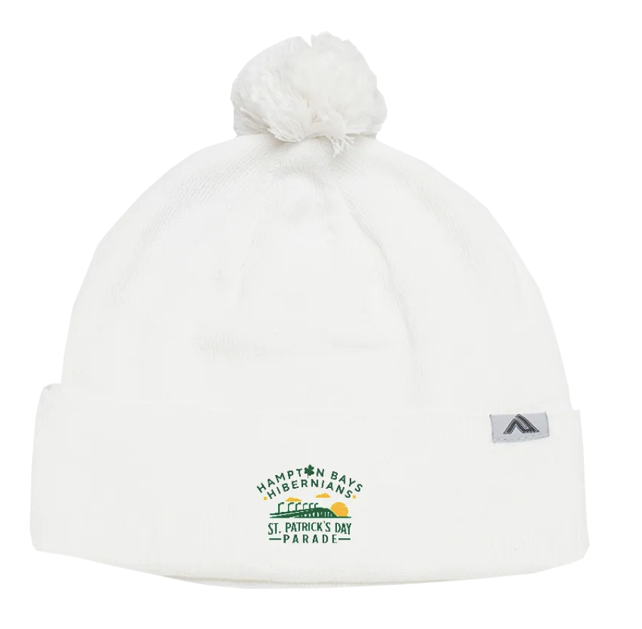 White winter hat with a pom-pom on top and a folded brim featuring a St. Patrick's Day parade logo with a train, the sun, and an Irish shamrock.
