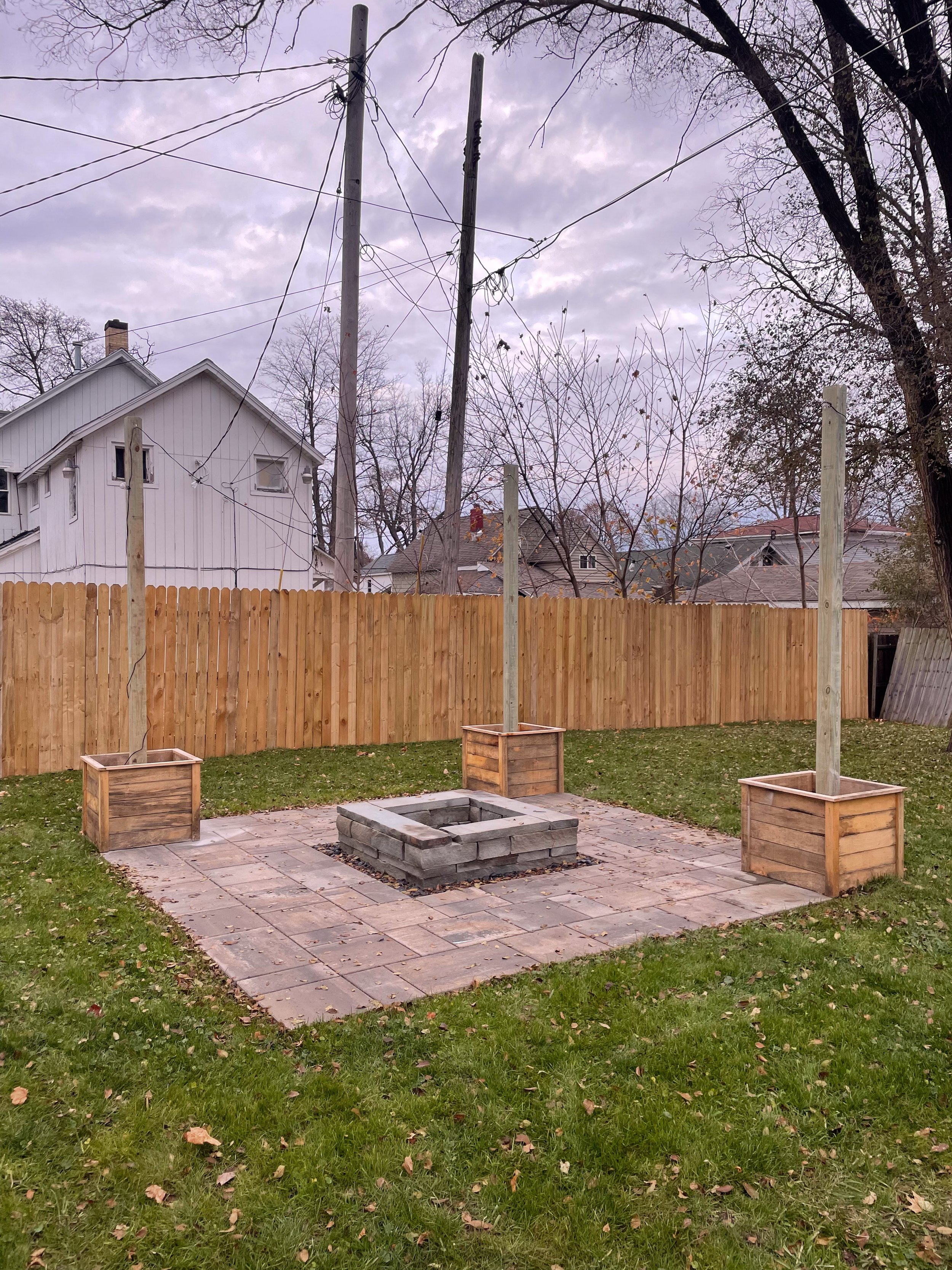Freshly cleaned brick paver patio in a West Michigan backyard, showcasing durable hardscape design with red and gray interlocking pavers and a lush green lawn