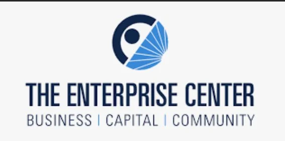 Logo of The Enterprise Center with a stylized blue and black circular design and the text 'THE ENTERPRISE CENTER' and 'BUSINESS | CAPITAL | COMMUNITY'.